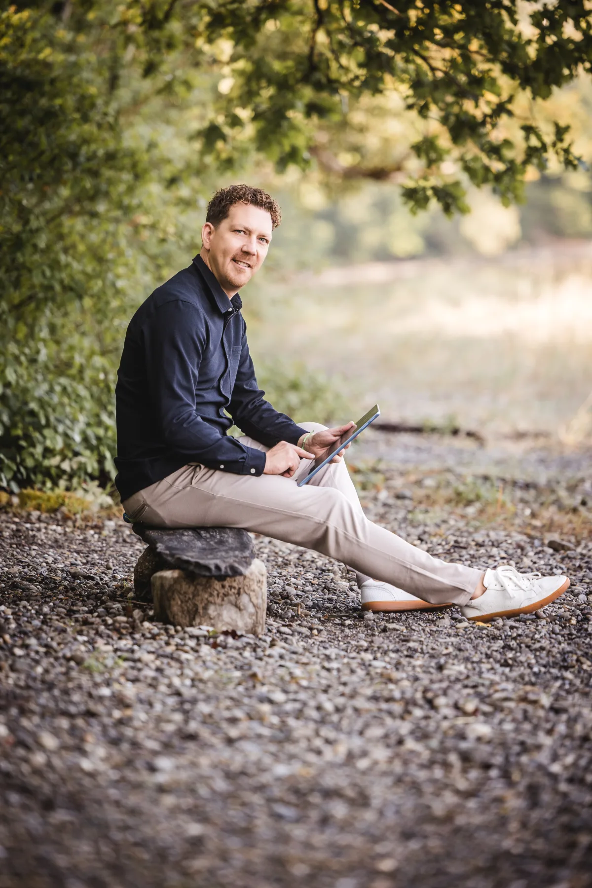 Michael Thiess sitzt mit einem Notizbuch in der Hand im Freien